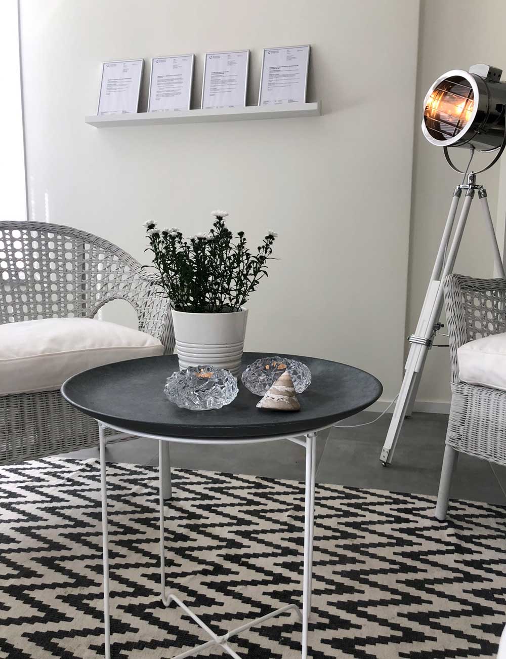Ett svart bord med vita ben och mönstrad matta.