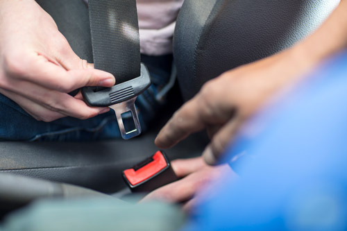 Person sätter på sig säkerhetsbälte.